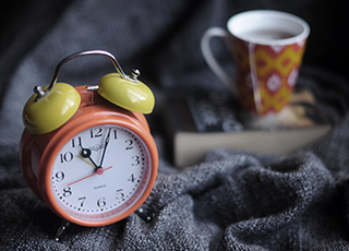 Old fashioned alarm clock and tea cup
