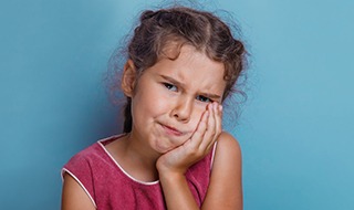 Little girl holding cheek in pain