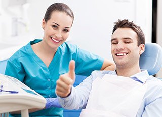 Smiling man in dental chair giving thumbs up